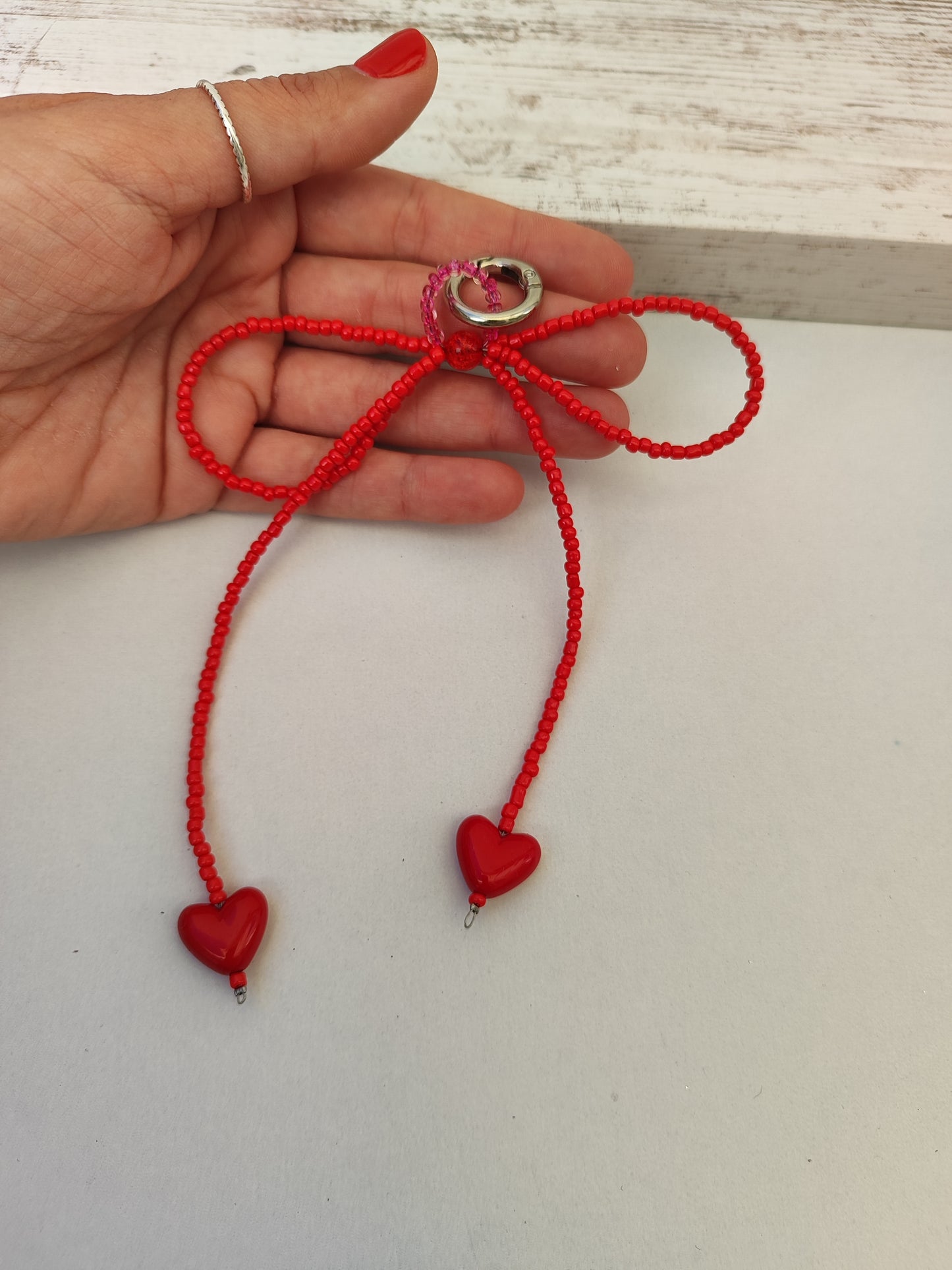 Bag charm φιόγκος από κόκκινες χάντρες και καρδιές.