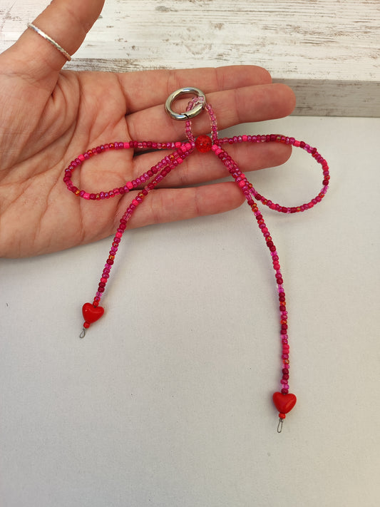 Bag charm φιόγκος από πολύχρωμες κόκκινες χάντρες και καρδιές.